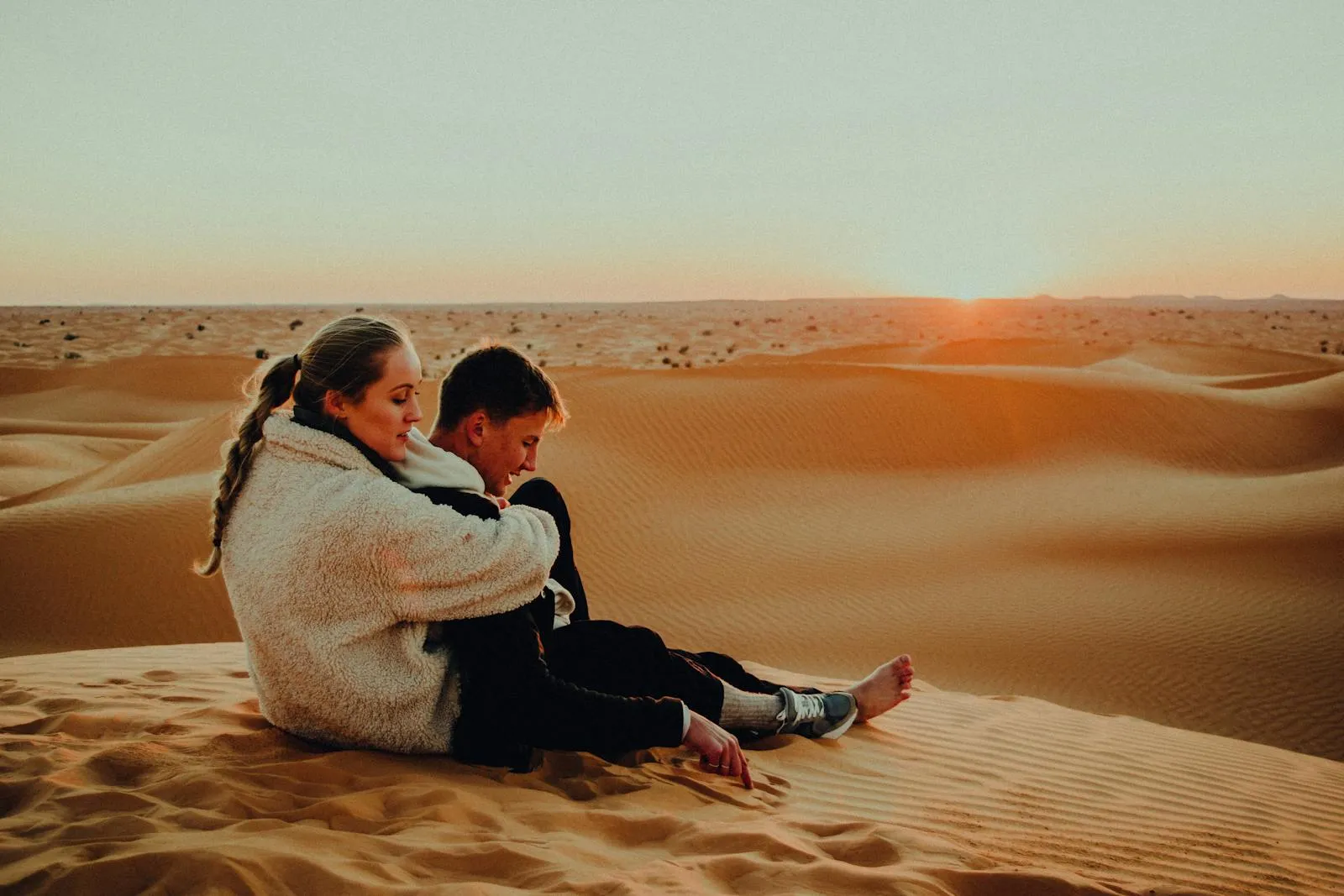 Couple sitting on a sand dune at sunset in Tunisia