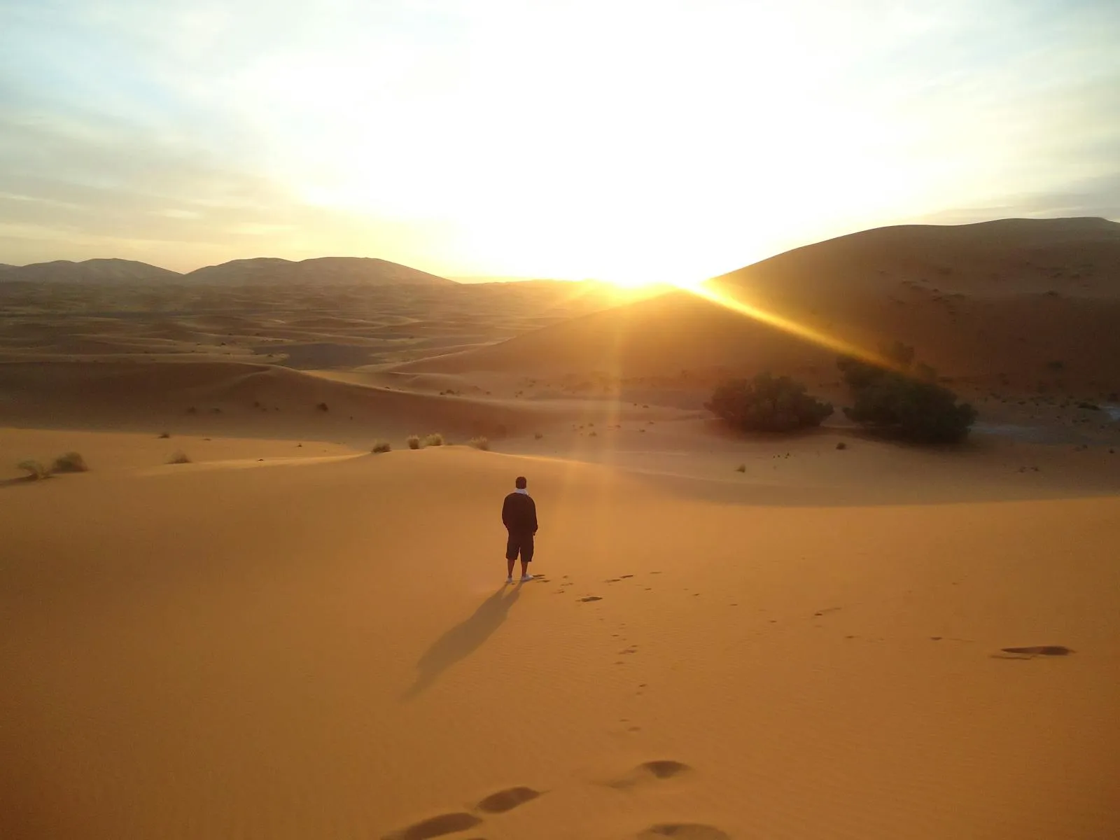Silhouette of a man walking on Sahara dunes at sunrise